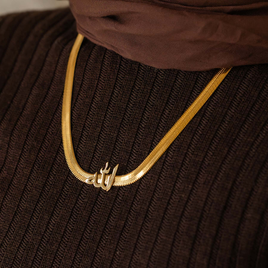 Gold necklace with a pendant on a brown textured fabric background