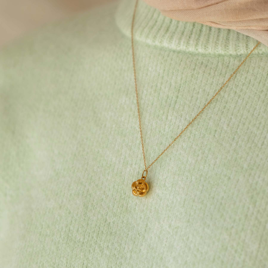 Gold necklace with a pendant on a light green sweater