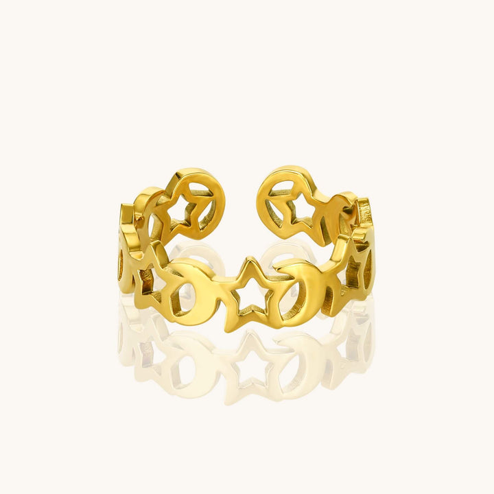 Gold ring with star and moon designs on a white background