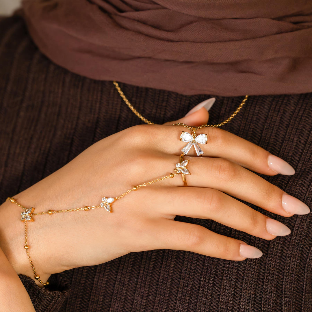 Hand wearing gold bracelet and rings with a brown background