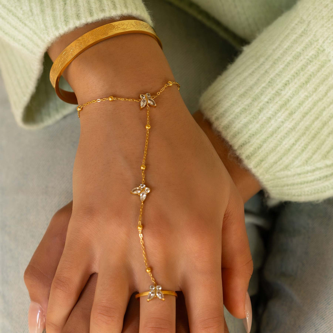 Gold bracelet and ring on a hand with a light green sweater