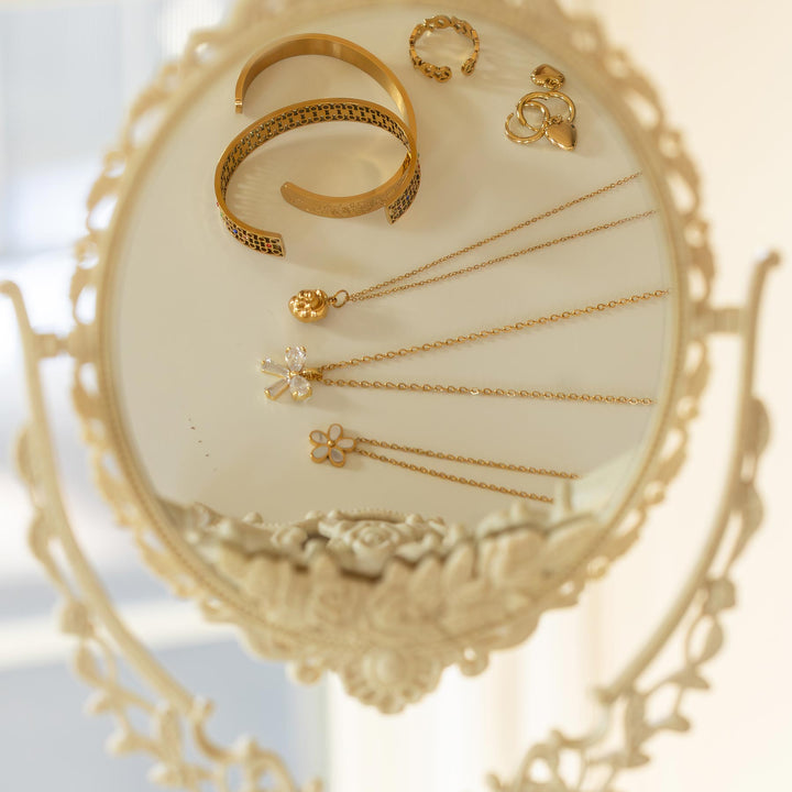 Gold jewelry including a bracelet, necklace, and earrings on an ornate stand.