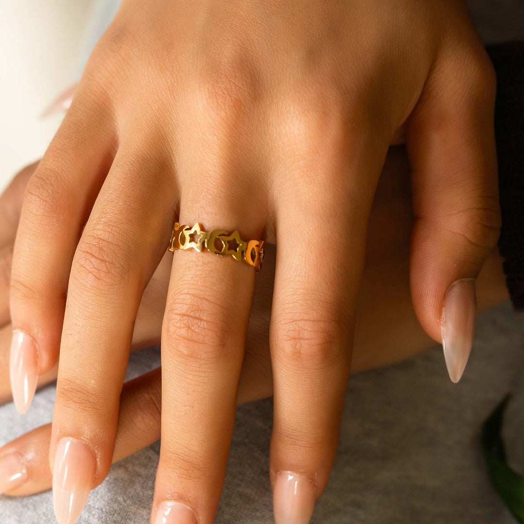 Close-up of a hand wearing a gold ring with a blurred background