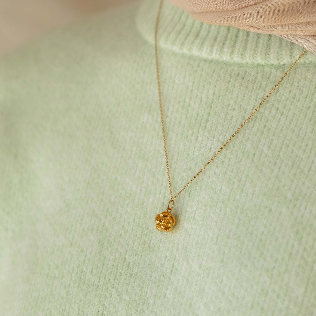 Gold necklace with a pendant on a light green sweater