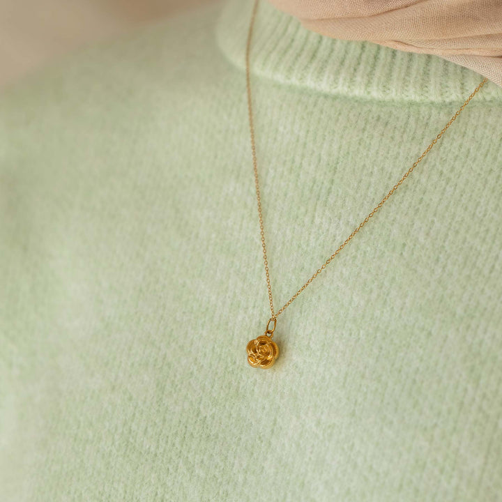 Gold necklace with a pendant on a light green sweater
